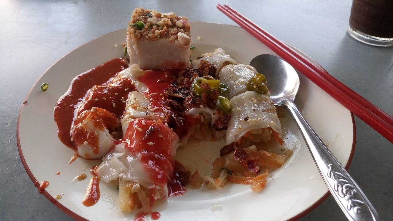 A portion of yam cake and chee cheong fun, rice noodle in translucent sheets, rolled with turnip filling, both eaten with chili sauce and black bean sauce
