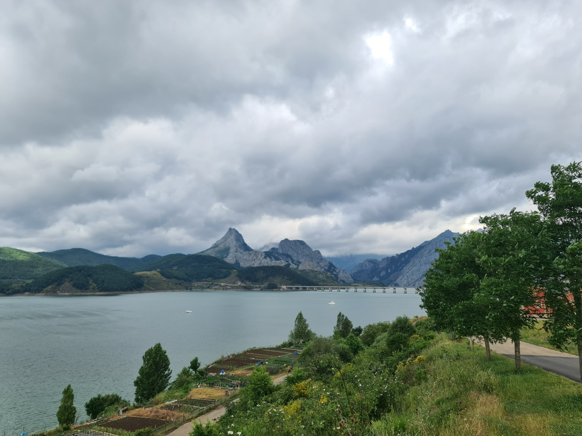Small orchards on the banks of the Riaño reservoir and the Riaño bridge and the Gilbo peak in the background.